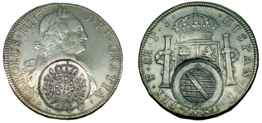 Moeda de 8 reales 1806 com Carimbo de Minas: No anverso, busto de Carlos IV ao centro e a legenda 'CAROLUS · IIII · DEI · GRATIA ·'. No Reverso, brasão de armas da Espanha e a legenda '· HISPAN · ET IND · REX · TS · 8R · J · P ·' (TS = Potosi)